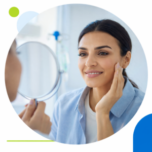 Mujer con piel saludable mirándose al espejo en entorno clínico.